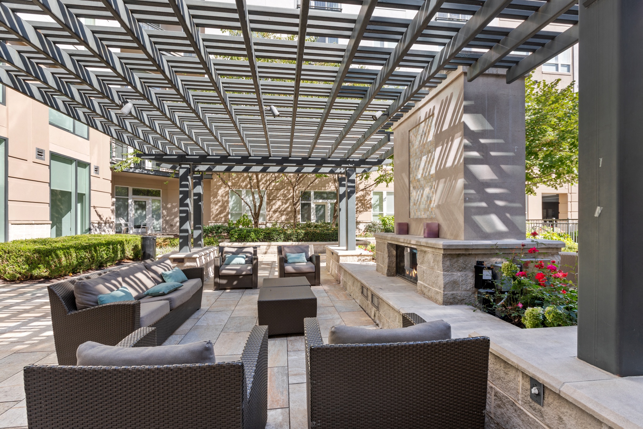 a lounge area with chairs and tables under a pergola